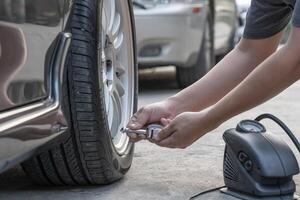 el hombre de asia usa el medidor de neumáticos analógico para verificar la presión de aire del automóvil de ruedas en el mantenimiento básico de la carretera por uno mismo foto