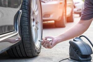 el hombre de asia usa el medidor de neumáticos analógico para verificar la presión de aire del automóvil de ruedas en el mantenimiento básico de la carretera por uno mismo foto