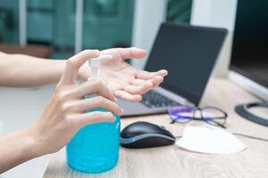 Women use Alcohol gel for protection and cleaning a hand after use computer,working at home concept photo