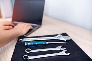 Technician use computer check detail of car repair and service  with wrench on black fabric on the table photo