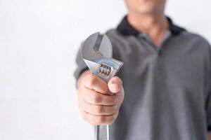 Technician hands of mechanic holding a wrench in service shop in white cement wall service concept of automobile photo