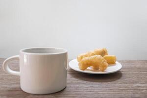 Close up Chinese deep fried dough sticks and coffee cup on wood table thai food concept photo