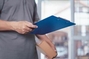 Delivery man hold the file and shopping box in home and protective mask for protection in delivery work photo