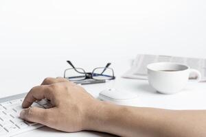 A man typing on keyboard with computer desktop in business concept and glasses coffee cup in background photo