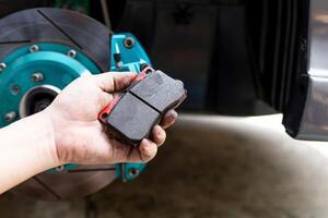 Close up old brake pad in hand a man for thickness check of pad in service work photo