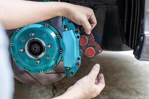 Man remove brake pad in brake caliper for thickness check of pad in service work photo