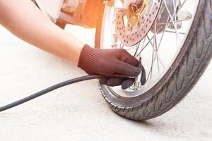 A man check inflator pressure of the tires with motorcycle with electric pump on road basic maintenance photo