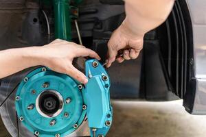 Man use open-end wrench adjust nut of nozzle brake caliper in brake fluid replacement for check and service brake system work photo