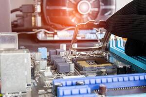 Electronic technician is putting the Socket of old CPU on the motherboard for check and service photo