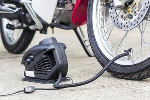 comprobación concepto aire presión y relleno aire en el llantas con motocicleta con eléctrico bomba en la carretera básico mantenimiento de automóvil foto