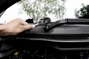 Close up Block wrench and hand a man remove nut lock on the wipers arm of car in service concept photo