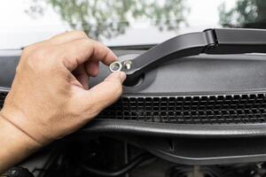 Close up nut the wipers arm in hand a man for lock in maintenance concept of car photo