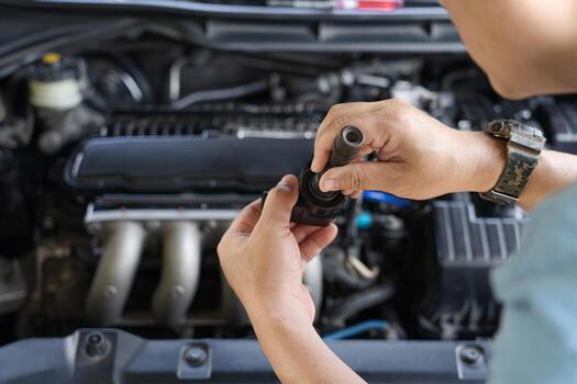Technician check old spark plug coil with Burn marks on engine coil in Maintenance service of gasoline  engine in garage photo
