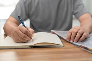 Man looking the newspaper for a new job and use pen write in notebook home while working at home photo