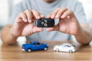 hombre participación remoto controlar de coche para bloquear y desbloquear coche en el anti-robo sistema y modelo juguete un coche en madera piso foto