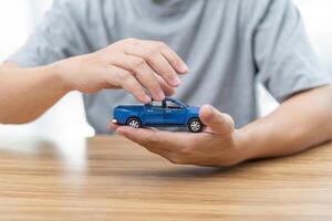 Close up on blue car toy model in hands protection for car insurance concept photo