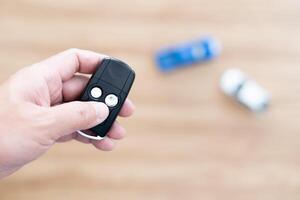 Close up hand of man holding and push remote control for lock and Un-lock car concept model toy a car in blur background photo