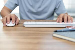 A man use mouse desktop computer and keyboard with credit card pen and note book on table working at home concept photo