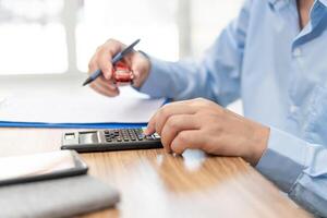 Car insurance concept Man use calculator pen and hold a accident toy car and write insurance documents on wood table photo