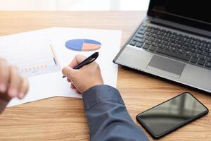 Business man working and analyzing on document data graph with laptop computer calculate for new project of business strategy at workplace. photo