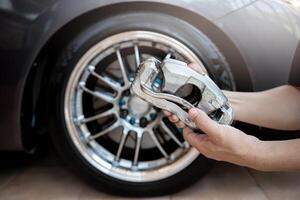 Car service run stop system concept close up caliper brake of car in hand a man and wheel of car in background photo