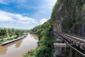 The railway at the foot of the mountain, next to the river and blue sky Tham Krasae, Kanchanaburi Province landmark of Thailand location photo