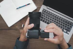 A man inserts battery into camera and use laptop computer in photography work photo