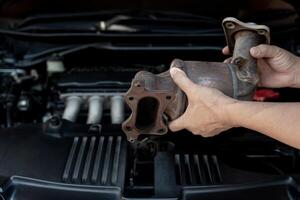 Close up old catalytic converter in hand Technician remove from engine gasoline car dust clogged condition on filter in service concept photo