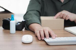 Postal man typing on keyboard input order list and check on the box for transport parcels and use desktop check stock order online order photo