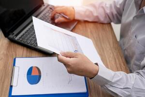 Business man working and analyzing on document data graph with laptop computer calculate for new project of business strategy at workplace. photo
