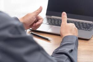 Business man thumbs up for work on the project successfully using computer and writing on a paper on desk in office photo