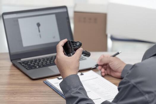 Hand a man hold coil spark plug engine gasoline use laptop computer check new part in stock compare and check auto parts for accuracy before replacing in periodic maintenance with check sheet on table photo