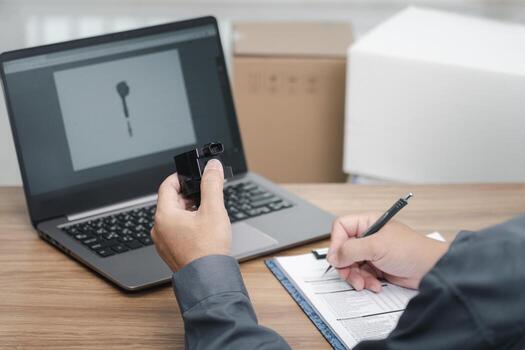 Hand a man hold coil spark plug engine gasoline use laptop computer check new part in stock compare and check auto parts for accuracy before replacing in periodic maintenance in the car service center photo