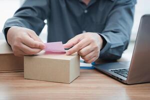 A man sticking notes on the parcel box follow order list in stock from computer Online order concept photo