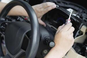 Close up hand Technician use screw driver remove and check car speedometer with check the point of damage and check for repair work in car service shop photo