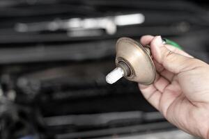 Close up hand car mechanic hold oxygen sensor of exhaust system of gasoline engine checking for faults in the exhaust system in the maintenance of the vehicle that has been used for a long time photo