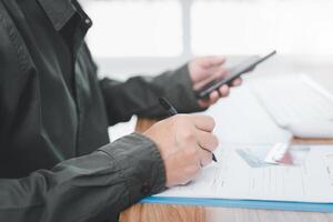 A man use pen write document and use smartphone working on the table photo
