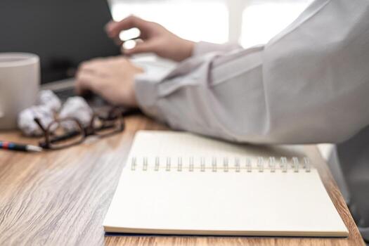 Close up notebook paper space on table with business man use computer laptop working in home office photo