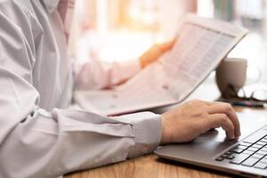 Relax time concept of a man use laptop reading news paper and coffee cup on the table photo