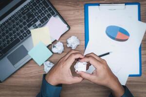 A man crunching papers in hand  strain feeling was frustrated with working failed with document in work office photo