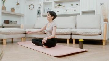 una joven asiática hace ejercicio en una alfombra de fitness, hace ejercicio en casa, un concepto de estilo de vida saludable video