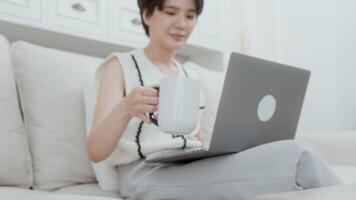 eine asiatische junge frau, die laptop-computer online verwendet, der zu hause arbeitet, lebensstil und telearbeitskonzept video