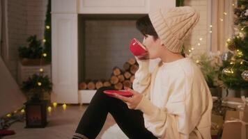 An Asian young woman wearing sweater enjoy winter season , reading book and drinking coffee at home video