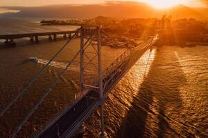 cable puente con puesta de sol en florianópolis, Brasil. aéreo ver foto