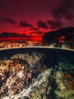 Tropical seascape with coral underwater and colorful sunset on the seashore, split view with artificial light in Bali photo