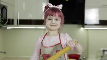 pequeno criança menina dentro a cozinha vestido dentro avental e cachecol com rolando PIN video