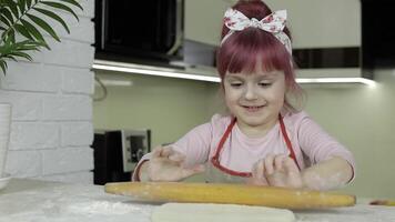 Koken pizza. weinig kind in schort rollen deeg met rollend pin Bij huis keuken video