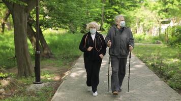 Active senior old man, woman training Nordic walking in park during quarantine video