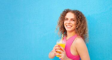 hermosa mujer sostiene delicioso naranja jugo, frío refrescante verano beber. azul fondo, aislado. al aire libre, caminar alrededor ciudad. contento. foto