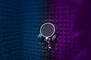 Microphone, headphones for singing, recording studio, black noise-cancelling walls, background, empty space for text, copy space.blue and purple light. photo